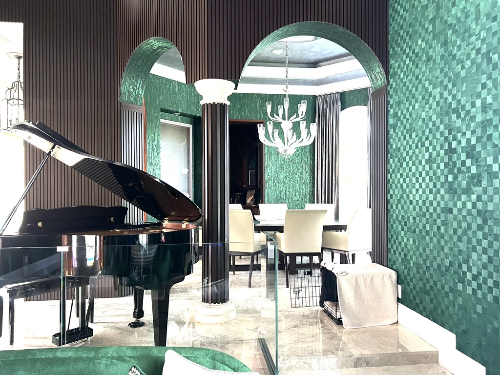 Music room with grand piano, deep green wall finish, dark millwork, and arched opening