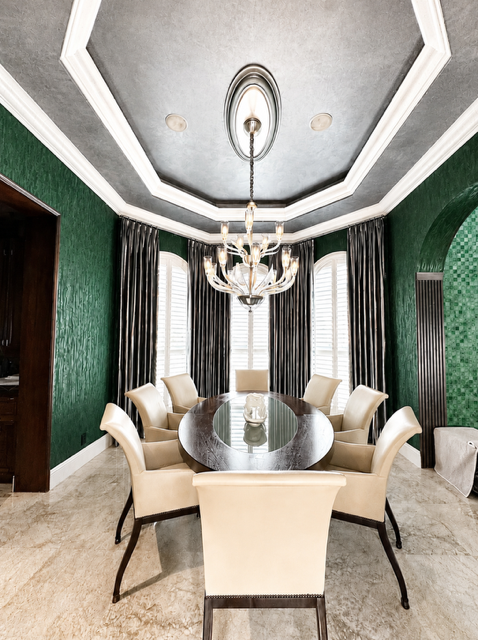 Formal dining room with deep green walls, long dining table, drapery, and sculptural chandelier