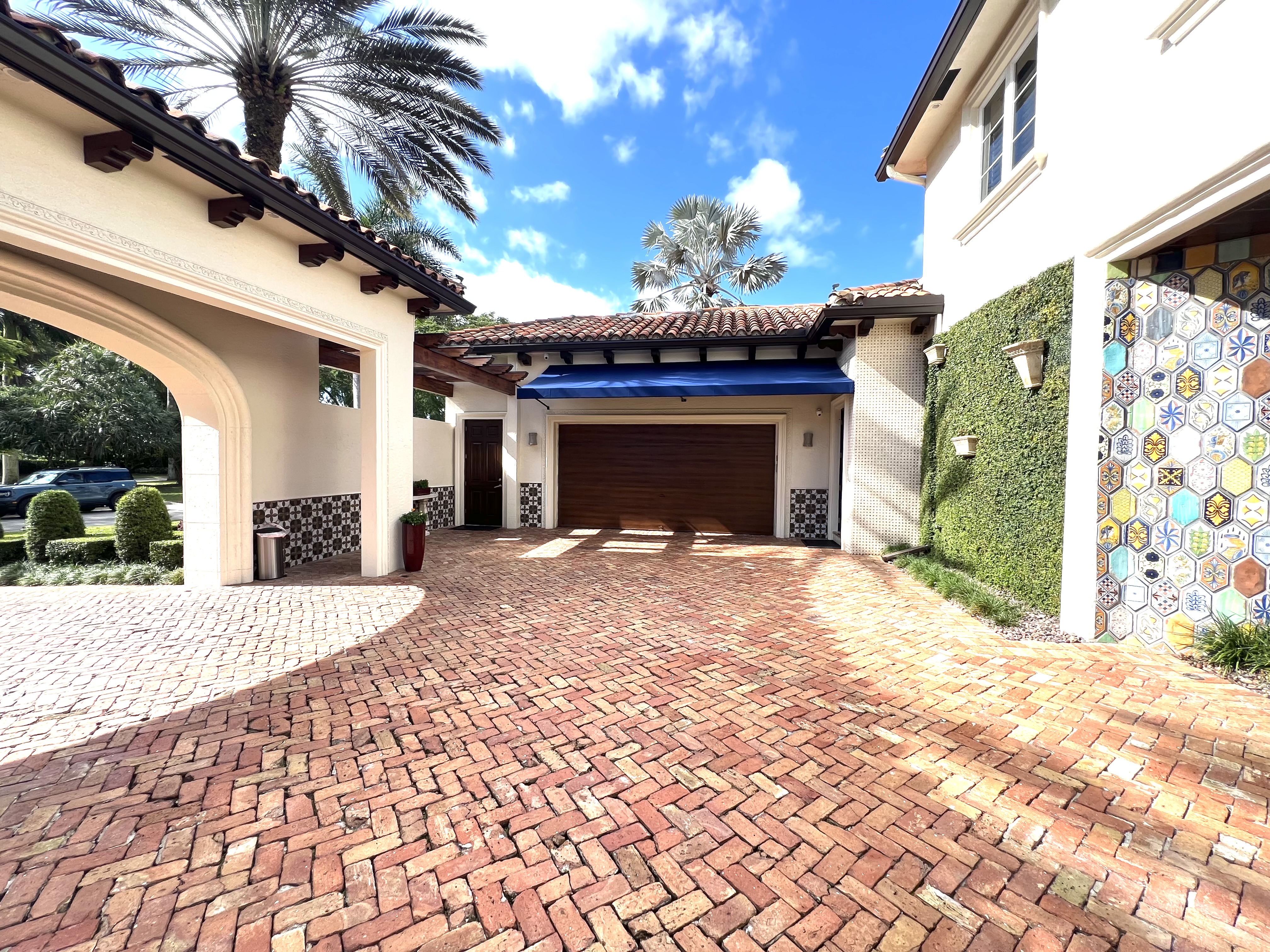 Brick motor court with wood garage door, blue awning, and decorative tile detail