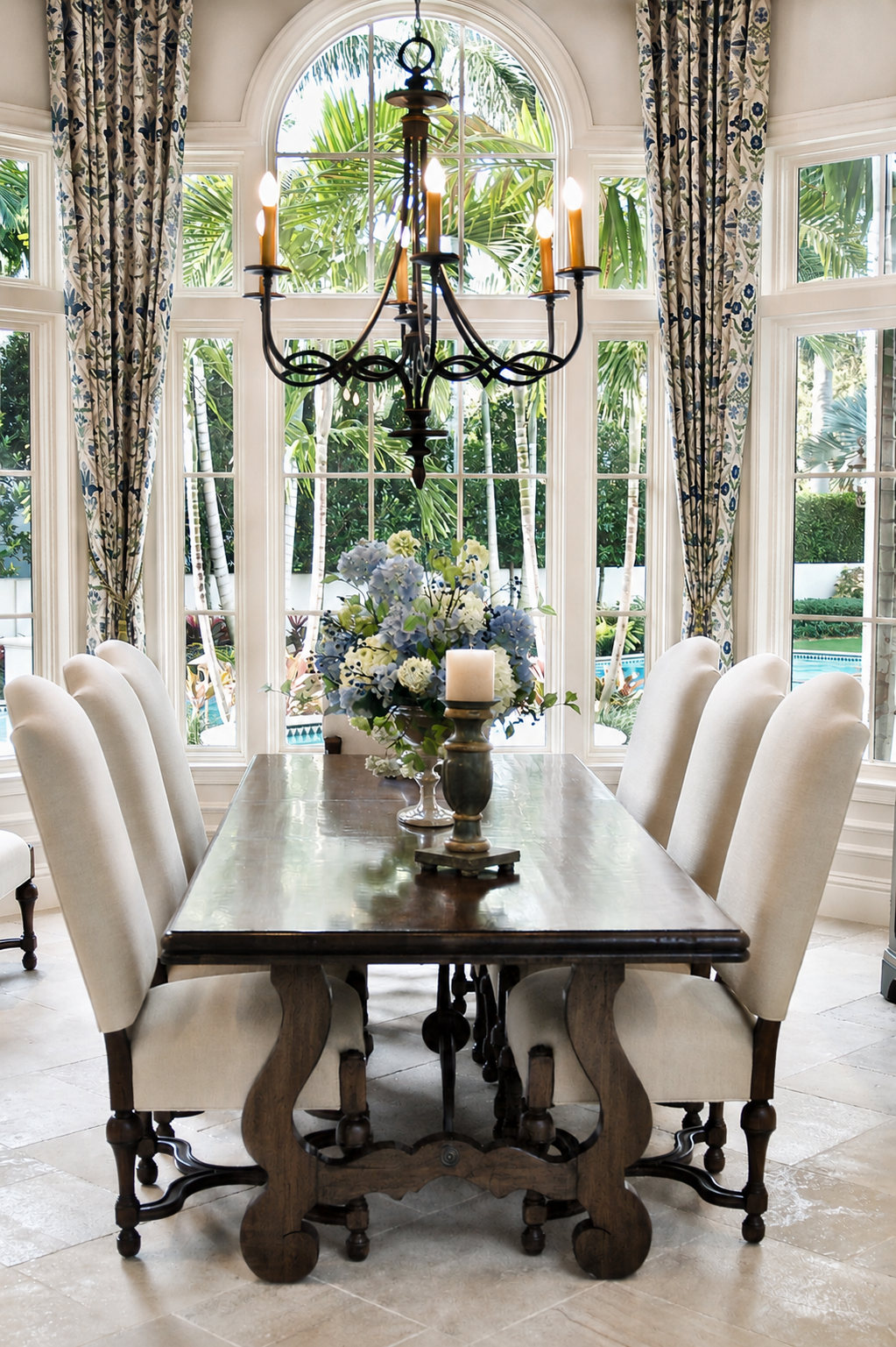 Formal dining room with tall arched window, chandelier, and upholstered chairs