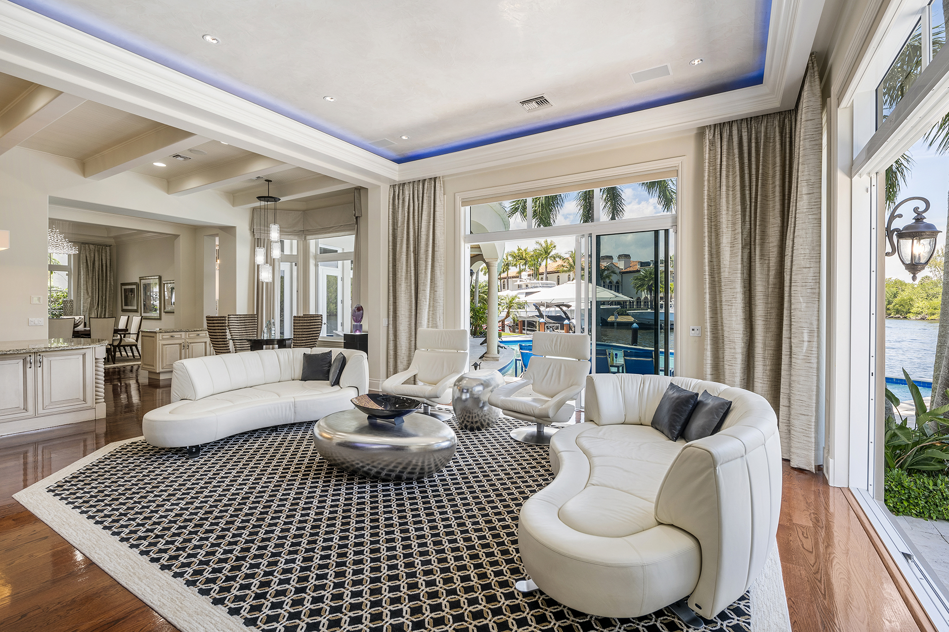 Contemporary luxury living room with sculptural white seating, dramatic patterned rug, and architectural ceiling lighting